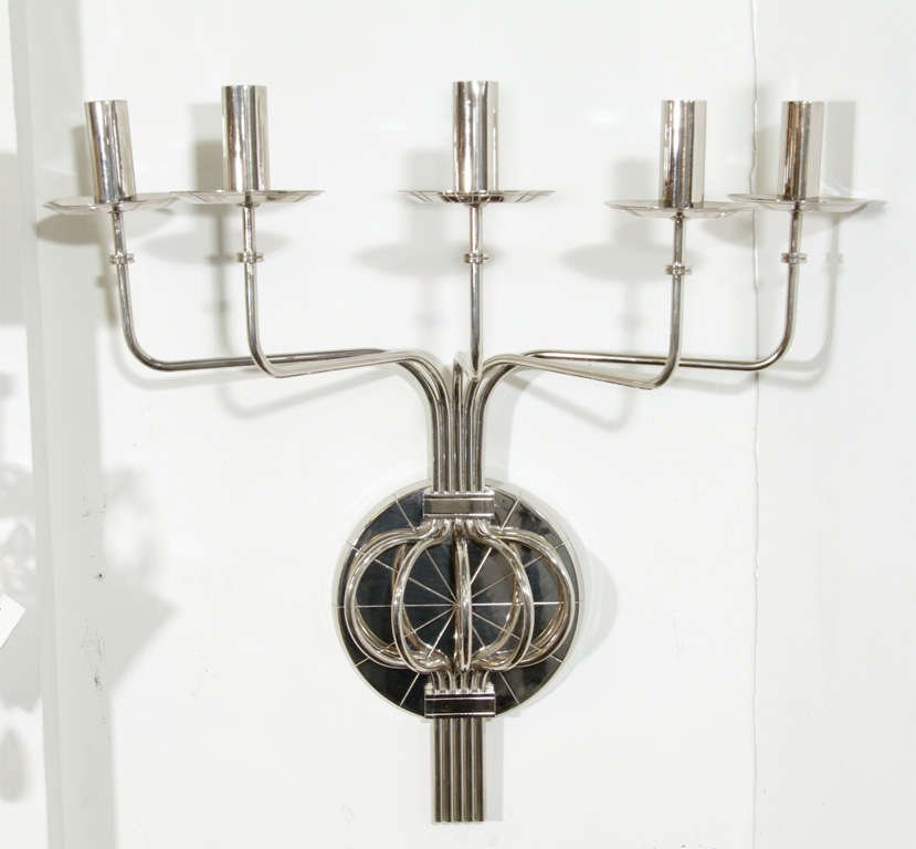 Modernist nickel five-arm candle sconce manufactured by Dorlyn Silversmiths and designed by Tommi Parzinger.  Each continuous arm extends from a bifurcating group mounted on a circular backplate with an incised sunburst pattern and features a loop